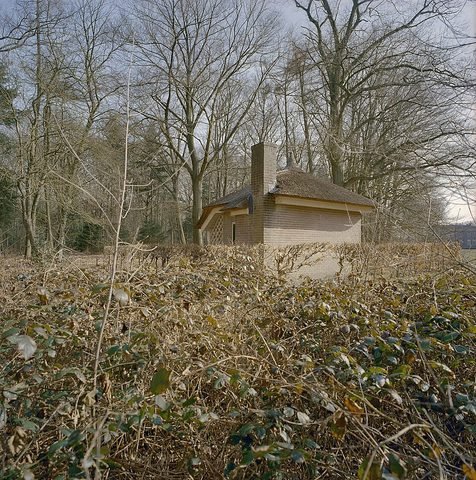 Een klein gebouw staat tussen bomen.