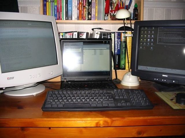 Een bureau met schermen en toestellen.
